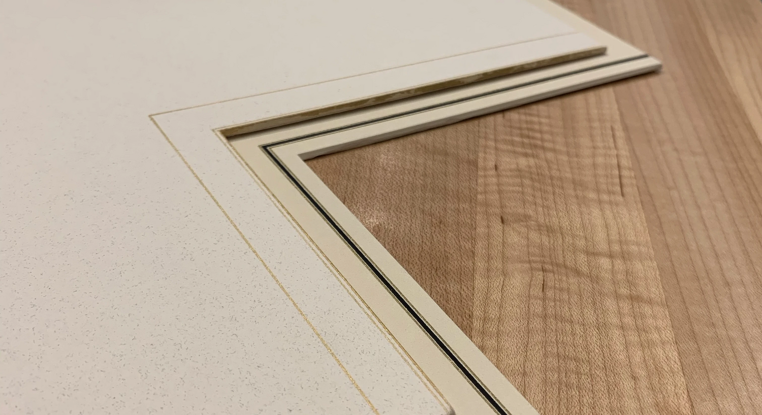 Ivory mat design with gold and black hand lines and a raised fillet